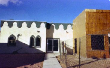 The masjid with cream walls, green trim and arched windows.