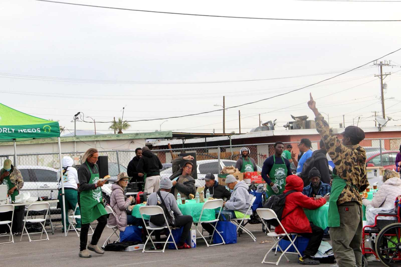 Neighbors sharing a meal under the green Al-Maun tent at Humanitarian Day on the Historic Westside.