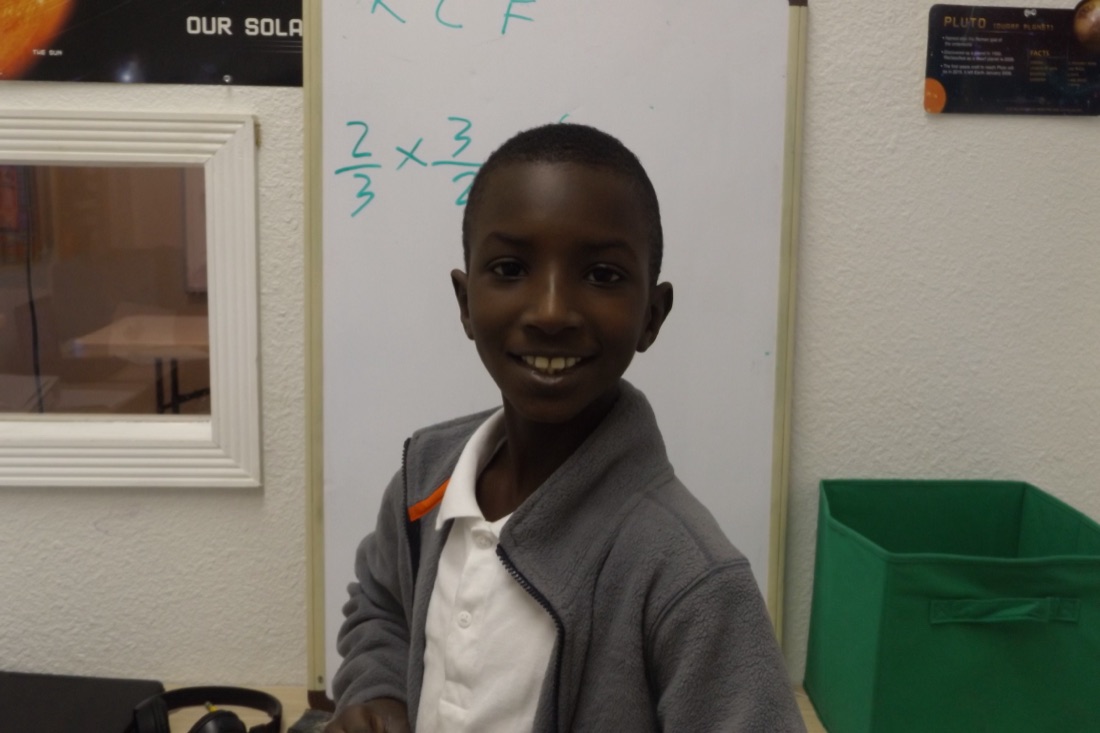 A boy standing at a whiteboard, working through a math problem.