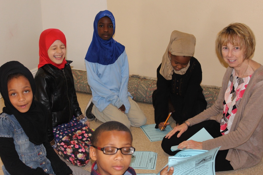 Children and a teacher working together on an activity around a table.