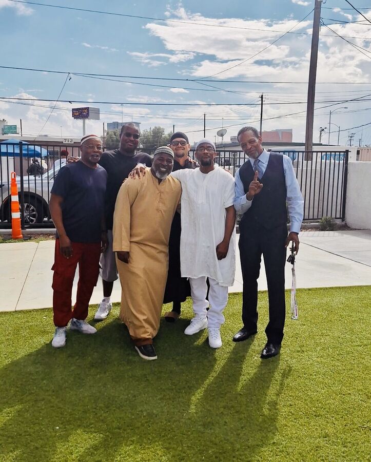 A group of men standing together on the grass outside.