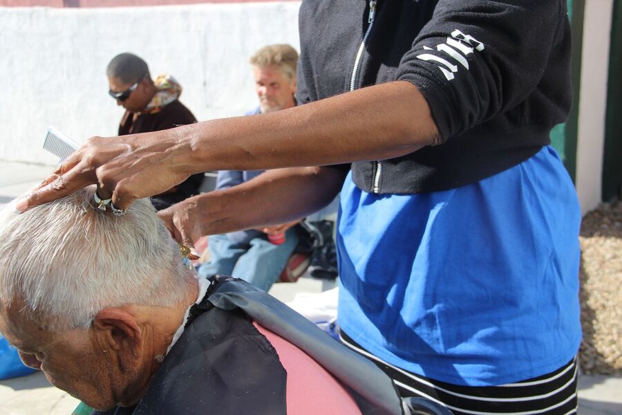 A barber giving an older man a free haircut at Day of Dignity.