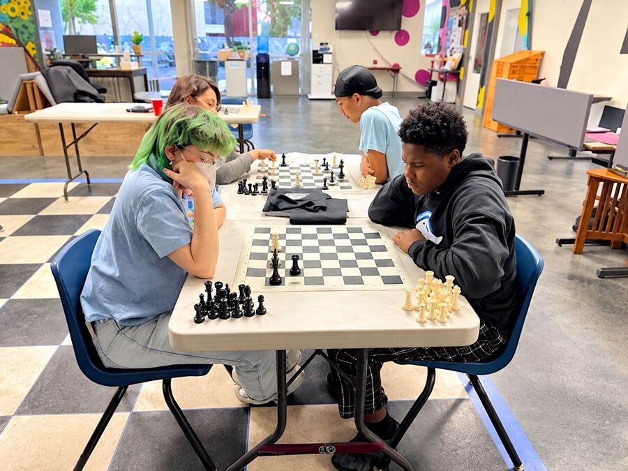 Two young people playing a game of chess at a table.